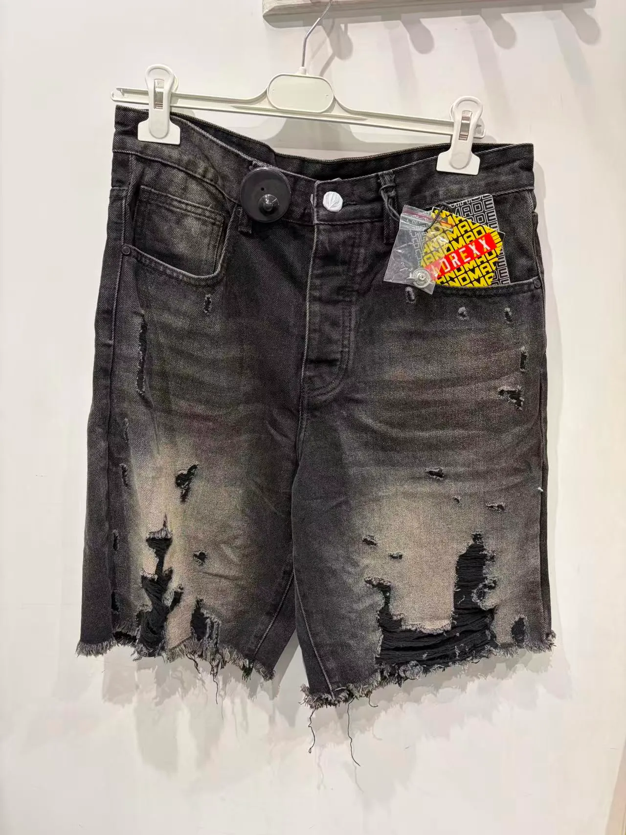 Pantaloncini neri slavati con strappi e toppa colorata, vista frontale
