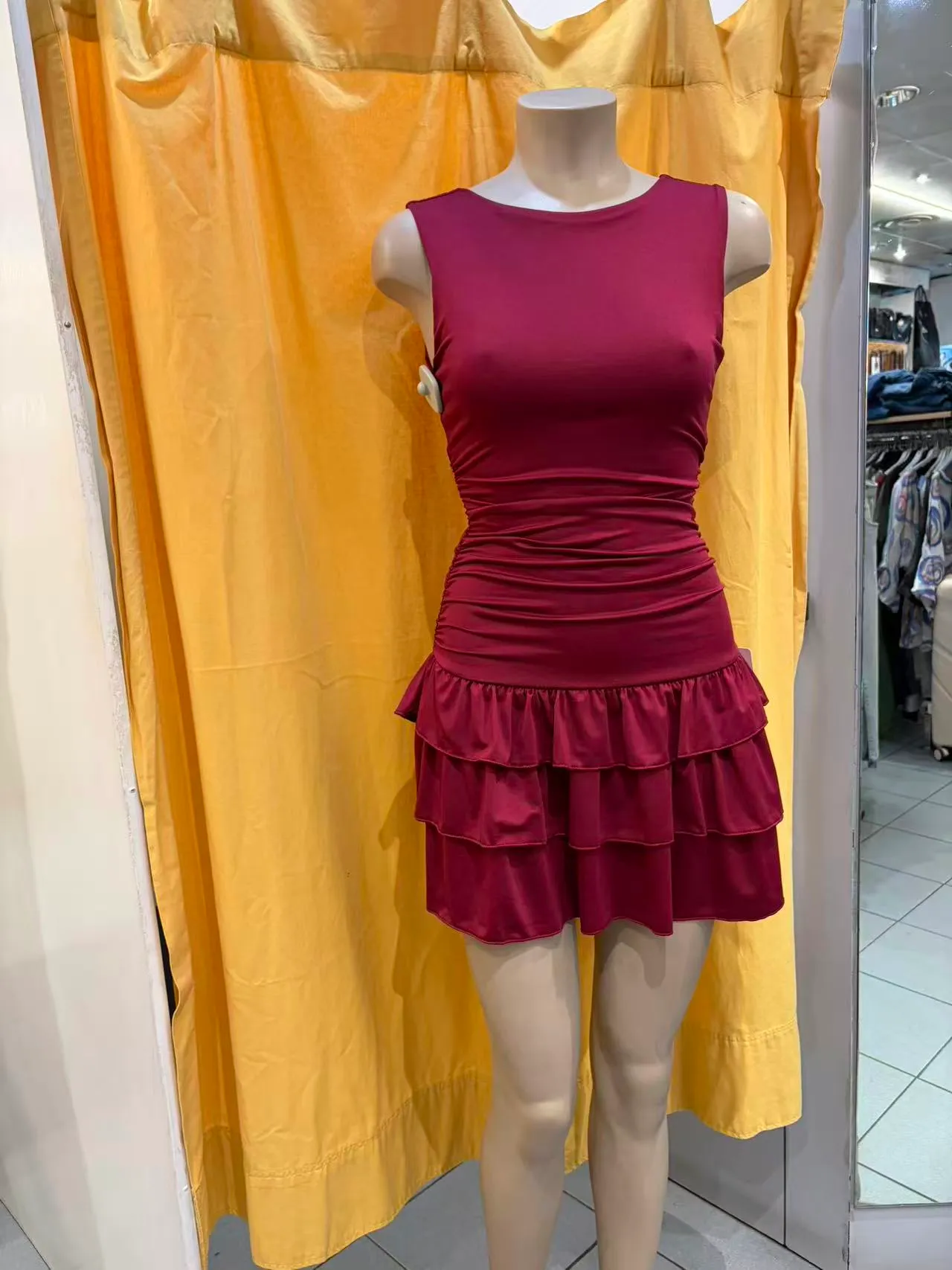 Abito corto bordeaux senza maniche con vita drappeggiata e gonna a balze, vista frontale